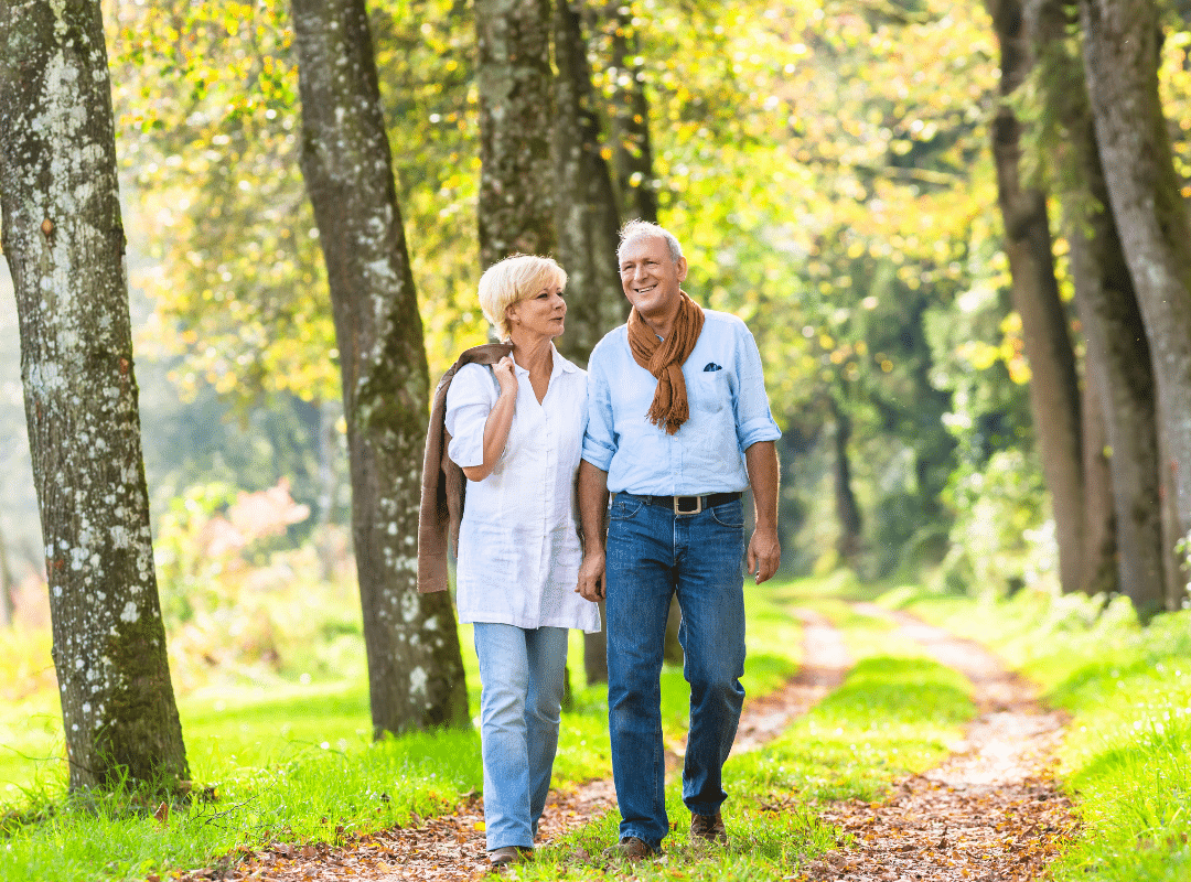 A senior couple strolls hand in hand through a serene forest