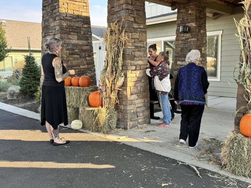 Residents and team members at The Lodge Retirement Community in Sisters, Oregon enjoy a cozy autumn afternoon surrounded by pumpkins and fall decorations.